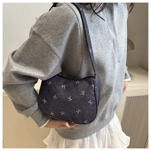 Close-up of small navy denim underarm bag with colorful butterfly bow embroidery detail