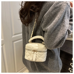 Detailed close-up of a white quilted mini crossbody bag with gold chain strap on a model