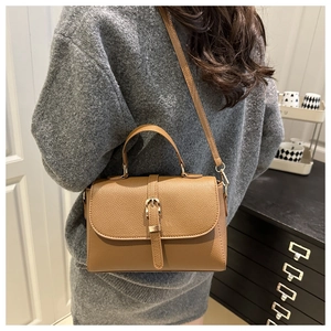 Brown lychee grain crossbody bag with gold buckle detail shown on a model's back