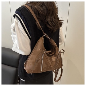 Sac bandoulière demi-lune marron mat avec rubans porté par un mannequin de dos