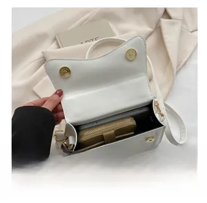 Interior view of white leather crossbody bag holding a smartphone and brown wallet