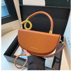Detailaufnahme der braunen Satteltasche mit goldenem Griff und Logo-Prägung