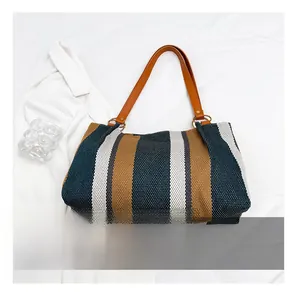 Detail view of large striped canvas tote bag with brown leather handles and size reference