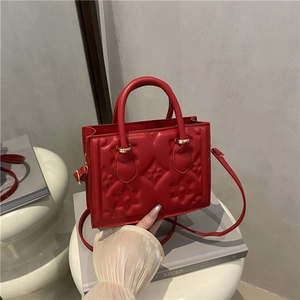 Red embossed leather handbag with chic floral pattern and gold hardware for women