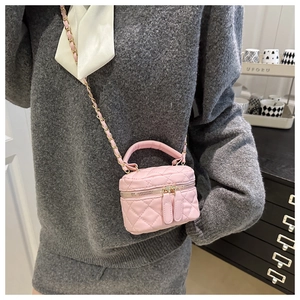 Detail view of pink quilted vanity bag with metal chain strap on model shoulder