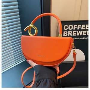 Detail der orangefarbenen Satteltasche mit goldenem Griff und Logo-Schriftzug