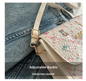 Detail of adjustable metal buckle and cute cartoon bear floral print on white leather bag