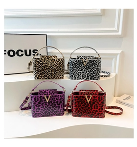 Detailed view of leopard print handbags in four colors with gold V-buckle and metal handles