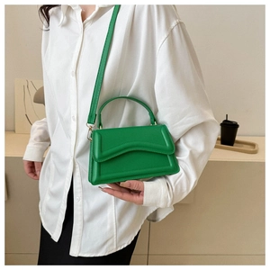 Detail of green leather handbag featuring wave pattern stitching and gold hardware