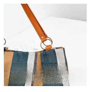 Detail of striped canvas tote with brown leather strap and gold metal ring hardware
