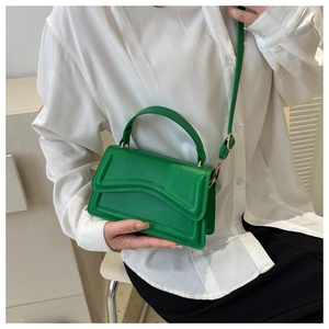 Detail of bright green leather handbag with wavy stitching and light gold hardware