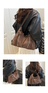 Detail of a large brown faux suede tote bag featuring bow ties and metallic zippers
