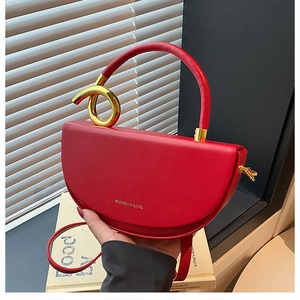 Detailaufnahme der roten Halbmond-Tasche mit goldenem Knotengriff und glattem Kunstleder