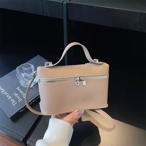Chic beige litchi grain leather box bag with top handle and silver zippers on black desk
