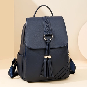 Navy blue faux leather backpack featuring woven patterns, a gold ring, and fringe details