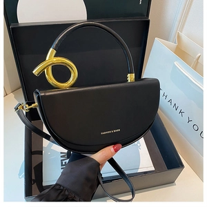 Detail der schwarzen Halbmond-Tasche mit goldenem Knotengriff und Riemen in einer Geschenkbox