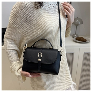 Detailed view of black pebbled leather handbag with gold buckle and adjustable strap