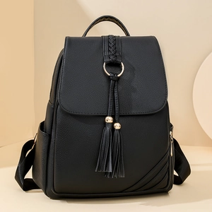 Women's black PU leather backpack with tassel detail and metal ring on cream background