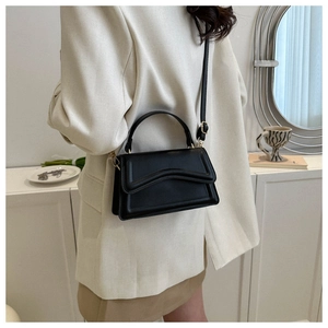 Detail of a black leather handbag with unique wave layered flap and gold hardware