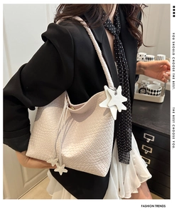 Detail of hand-woven cream white bucket bag with a star charm and thin shoulder strap