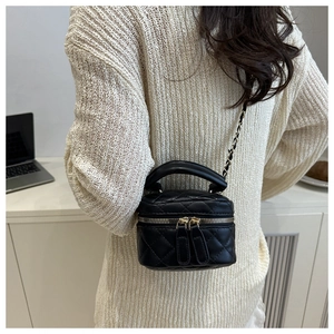 Dettaglio di una mini borsa trapuntata nera con catena indossata da una modella