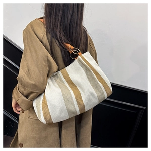 Detail of striped canvas tote bag showing orange leather strap and woven texture