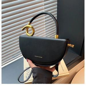 Detail einer schwarzen Satteltasche aus Leder mit goldenem Knoten-Griff und Logo