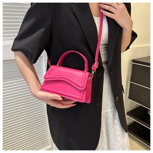 Rose pink mini crossbody bag with wavy stitching worn with a black blazer and white skirt