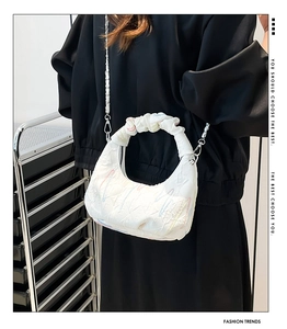 Detail of white seersucker crossbody bag with color contrast stitching and silver chain strap