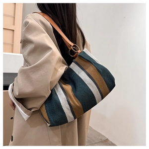 Detail of striped canvas tote bag with brown leather strap and gold ring attachments
