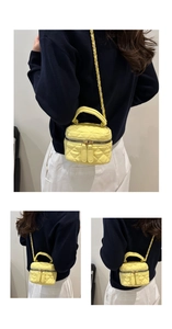 Detail of yellow quilted crossbody bag with metal chain strap and top handle design