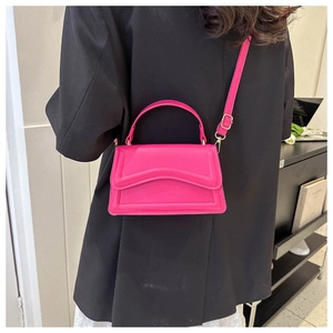 Detail of rose pink handbag with wavy flap edge and gold hardware worn cross-body