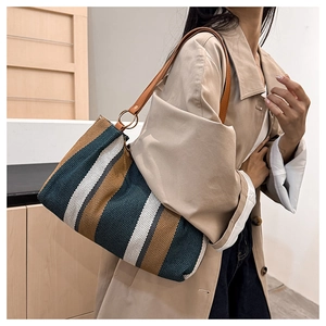Close-up of green and brown striped canvas tote bag with leather handles and metal rings