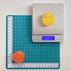 Detail view of shell-shaped resin phone grips with gold foil inlay on a measuring scale