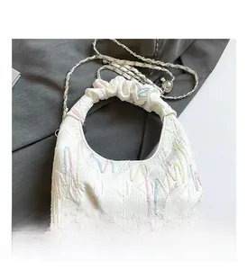 Detail of white quilted handbag with colorful wave embroidery and gold chain strap