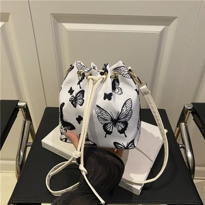 Borsa a secchiello bianca minimalista con stampa a farfalla su sedia in pelle