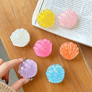 Colorful resin shell phone griptok set with sparkling glitter foil on wooden desk