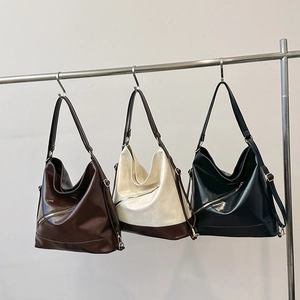 Three large contrast tote bags with metal zippers in brown, beige, and black leather
