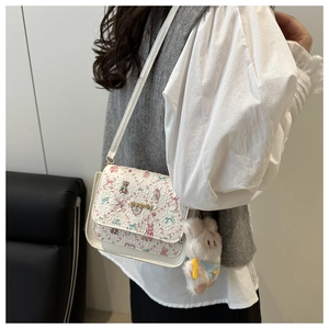Details der weißen Umhängetasche mit Cartoon-Print, Gold-Logo und Plüsch-Hasenanhänger