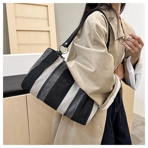 Close-up of woven canvas texture and black leather strap with gold hardware detail