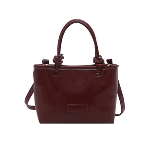 Deep red shiny leather crossbody bag with knot handles and rectangular silhouette