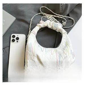 Detail of white quilted bag featuring colorful wave embroidery and leather chain strap