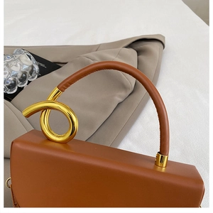 Detailansicht der braunen Ledertasche mit einzigartigem goldverzerrtem Metallgriff