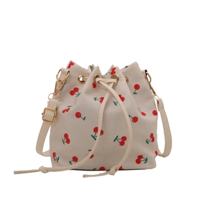 Elegant white bucket bag with red cherry prints and golden hardware in a studio shot