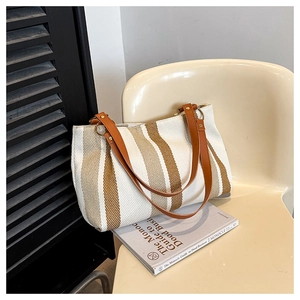 Detail of striped canvas tote bag showing textured fabric and brown leather straps