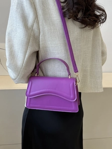 Fashionable purple PU leather handbag with wavy flap and gold hardware on model