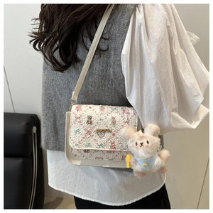 Detail of floral crossbody bag with teddy bear prints and plush rabbit charm
