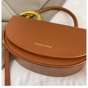 Detailansicht einer braunen Satteltasche aus Leder mit markantem goldenem Metallgriff