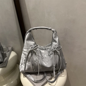 Sac hobo en satin argenté avec nœuds délicats et fermetures éclair sur un support