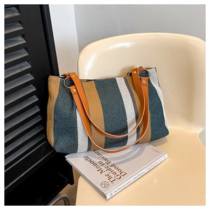 Detailed close-up of large tri-color striped woven tote bag on a beige chair
